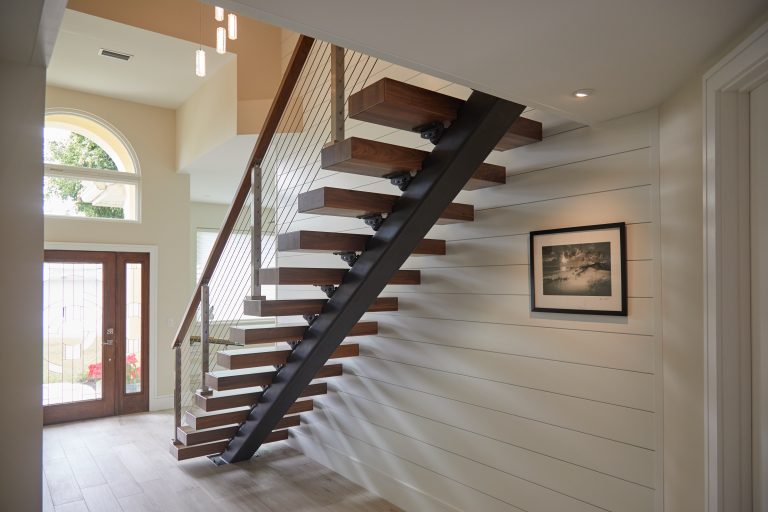 Floating stairs in an open foyer focusing on the steel stringer.