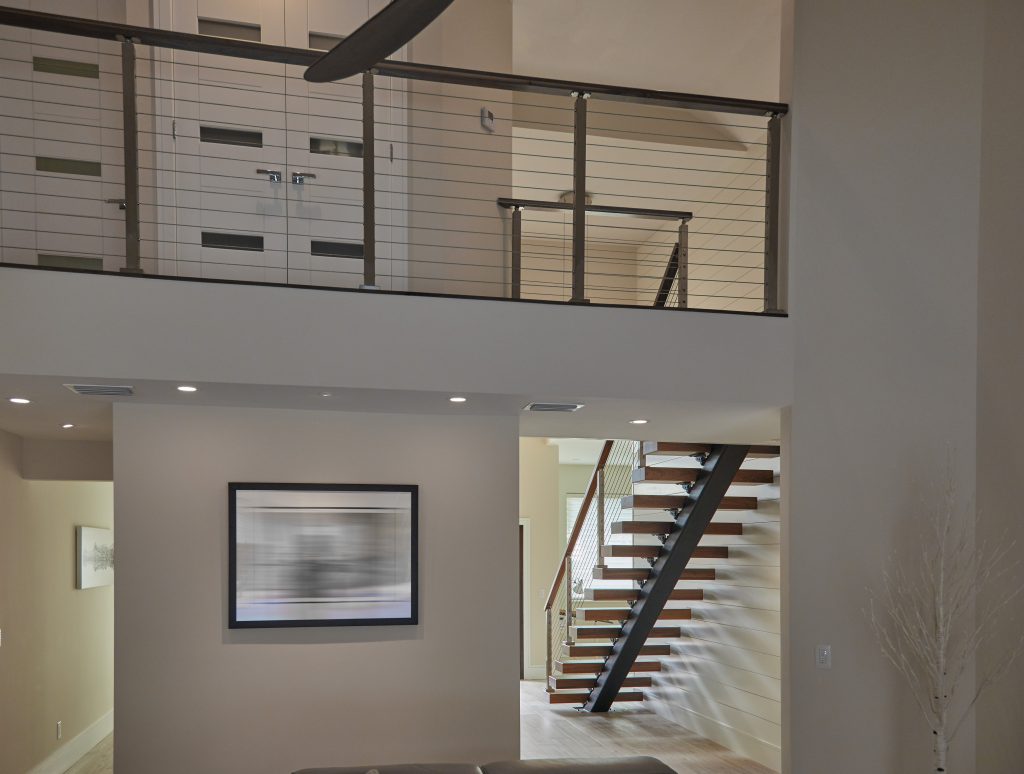 Wide shot of a floating staircase and balcony railing in an open concept home.