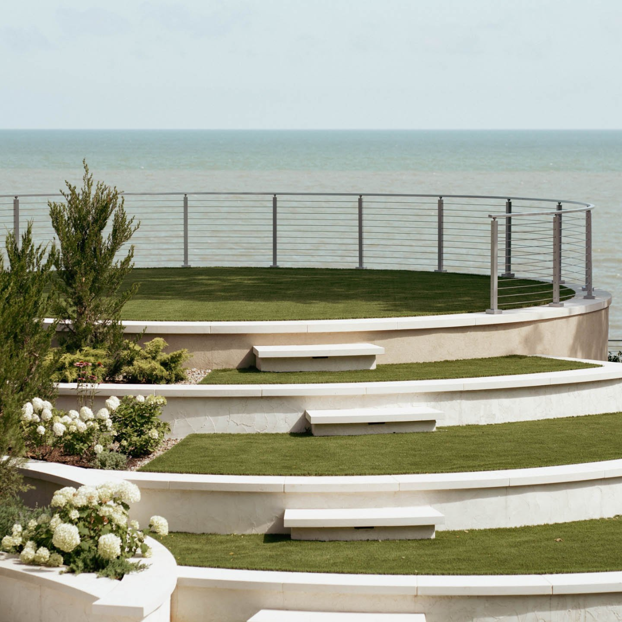 A view of a curved rod railing from Viewrail with metal posts and handrail overlooking a lake.