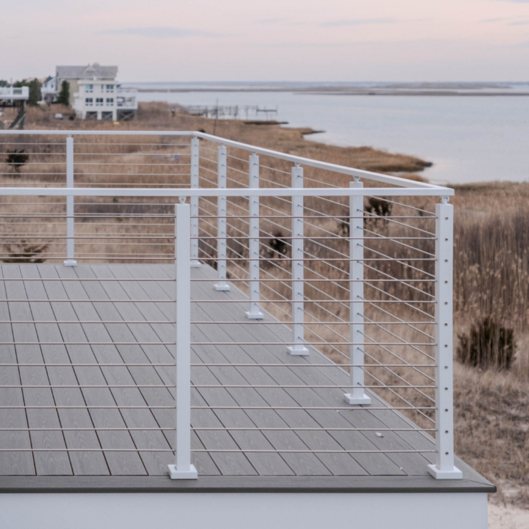 A deck with a white Viewrail Signature Cable railing overlooks the ocean