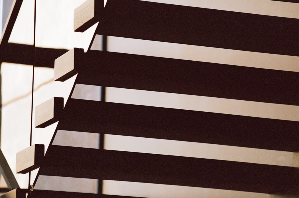 A close up view of a few of the cantilevered stairs and glass railing in low light.