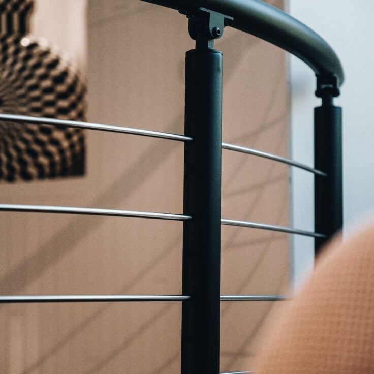 Close up image of the curved railing with rod infill and black powder-coated posts and handrail.